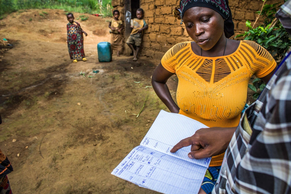 Olipa Ningabiye a beneficiary of the graduation model program showing her notebook where she recorded her activities generating revenues