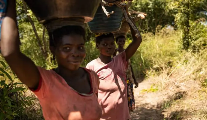 Women return from farmland with baskets of vegetables and firewood, Kapotongo village, Manono Territory, DRC.