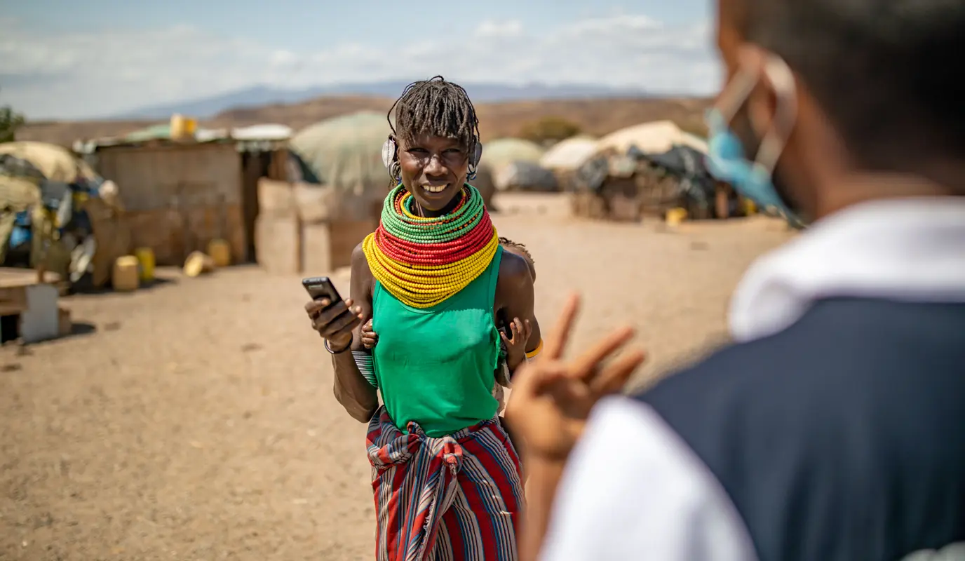 Akiru Leakanoi is guided through the process of receiving a mobile cash transfer