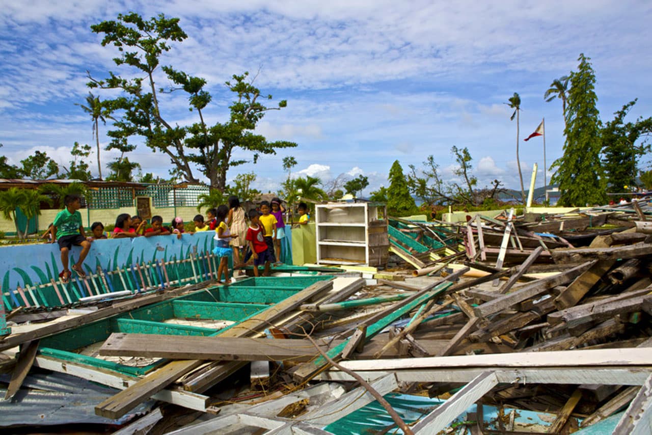 School kids look at their destroyed classroom