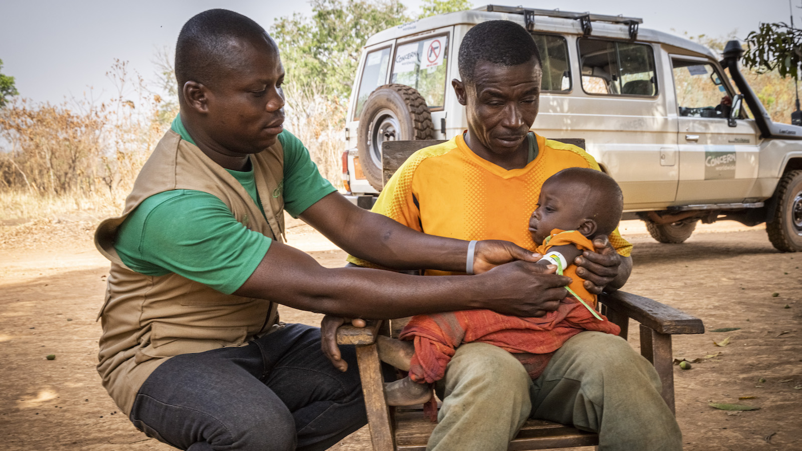 Lauran Moumbe, Concern community sensitiser and Alain* and baby Christian* in Ngata village outside their home. (Photo: Ed Ram/Concern Worldwide)