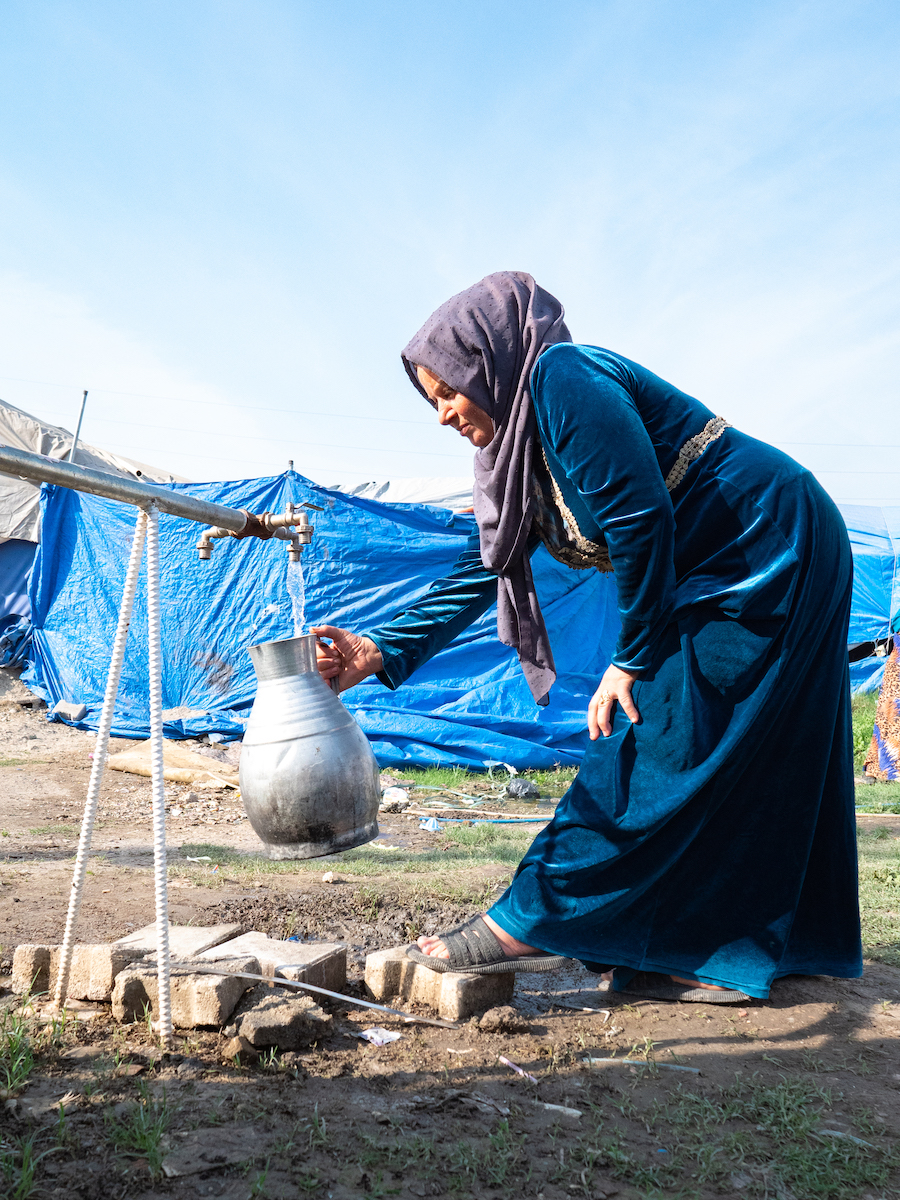 Darine* gets water from the water tank. Water tanks distributed and installed by Concern through the ECHO programme. These tanks provide a critical need for these families. (Photo: Gavin Douglas/Concern Worldwide)