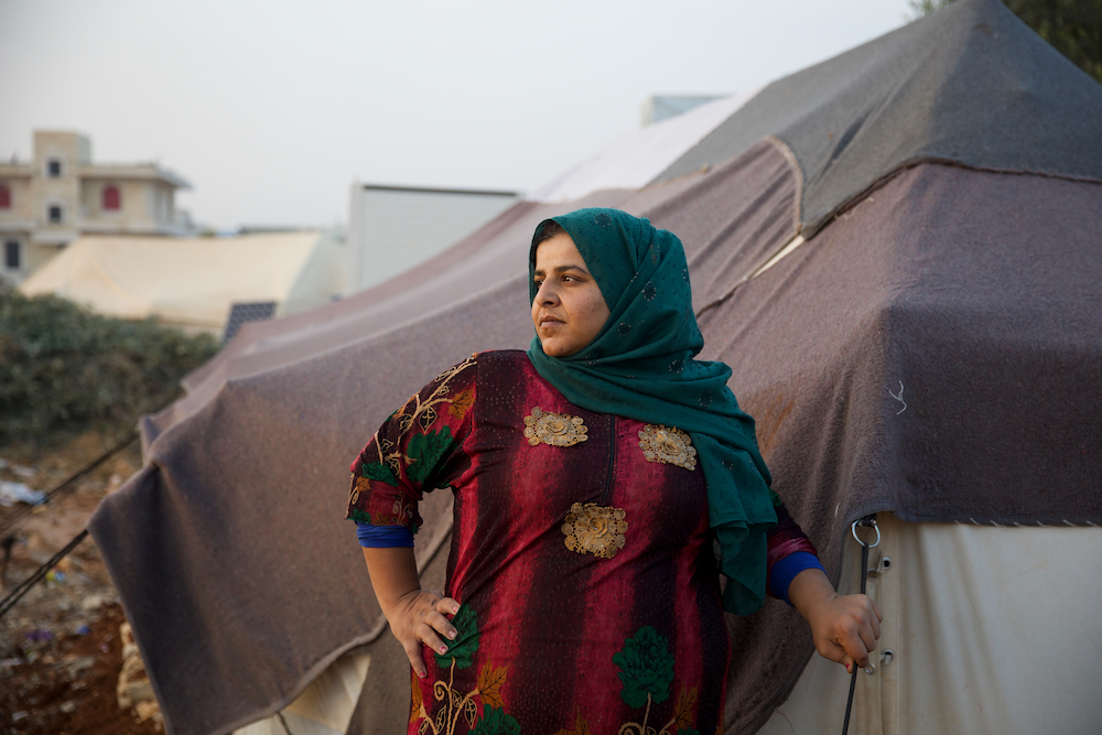 Ramya* (29) stands in front of her tent, trying to secure its edges for fear of a storm that will cause rainwater to leak inside,