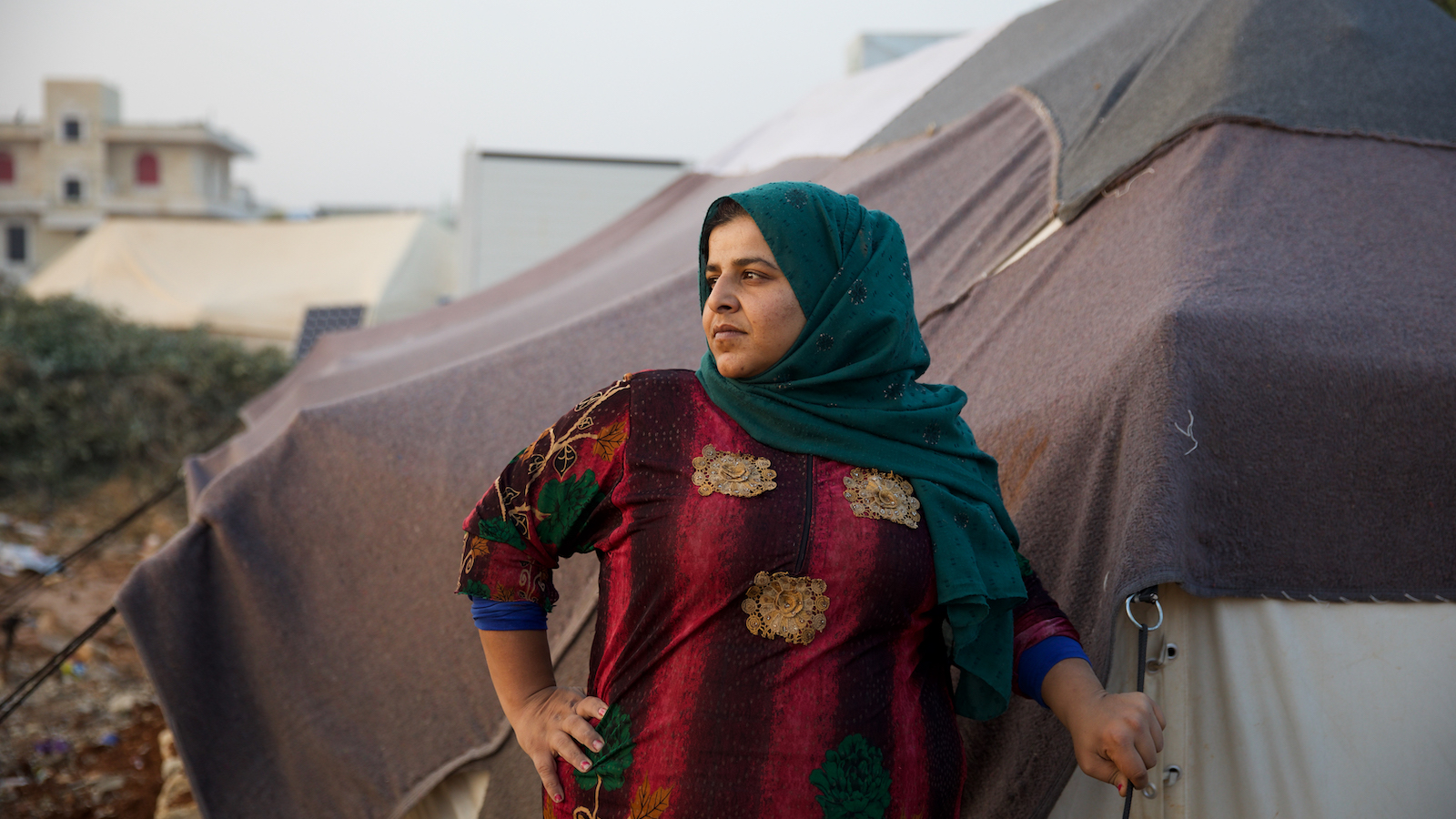 Ramya* (29) stands in front of her tent, trying to secure its edges for fear of a storm that will cause rainwater to leak inside. (Photo: Ali Haj Suleiman/DEC/Fairpicture)