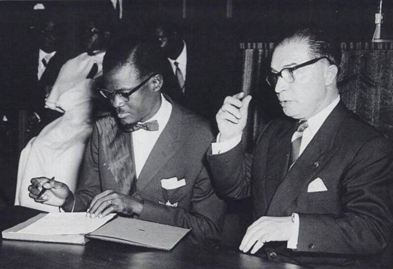 Patrice Lumumba signs the document granting independence to present-day Democratic Republic of Congo next to Belgian Prime Minister Gaston Eyskens (Photo: Congopresse / Wikimedia Commons)