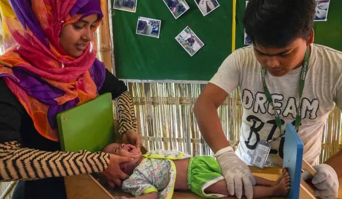 Clinic staff measures a baby at the Jamtoli Outpatient therapeutic clinic, Ukhiya.