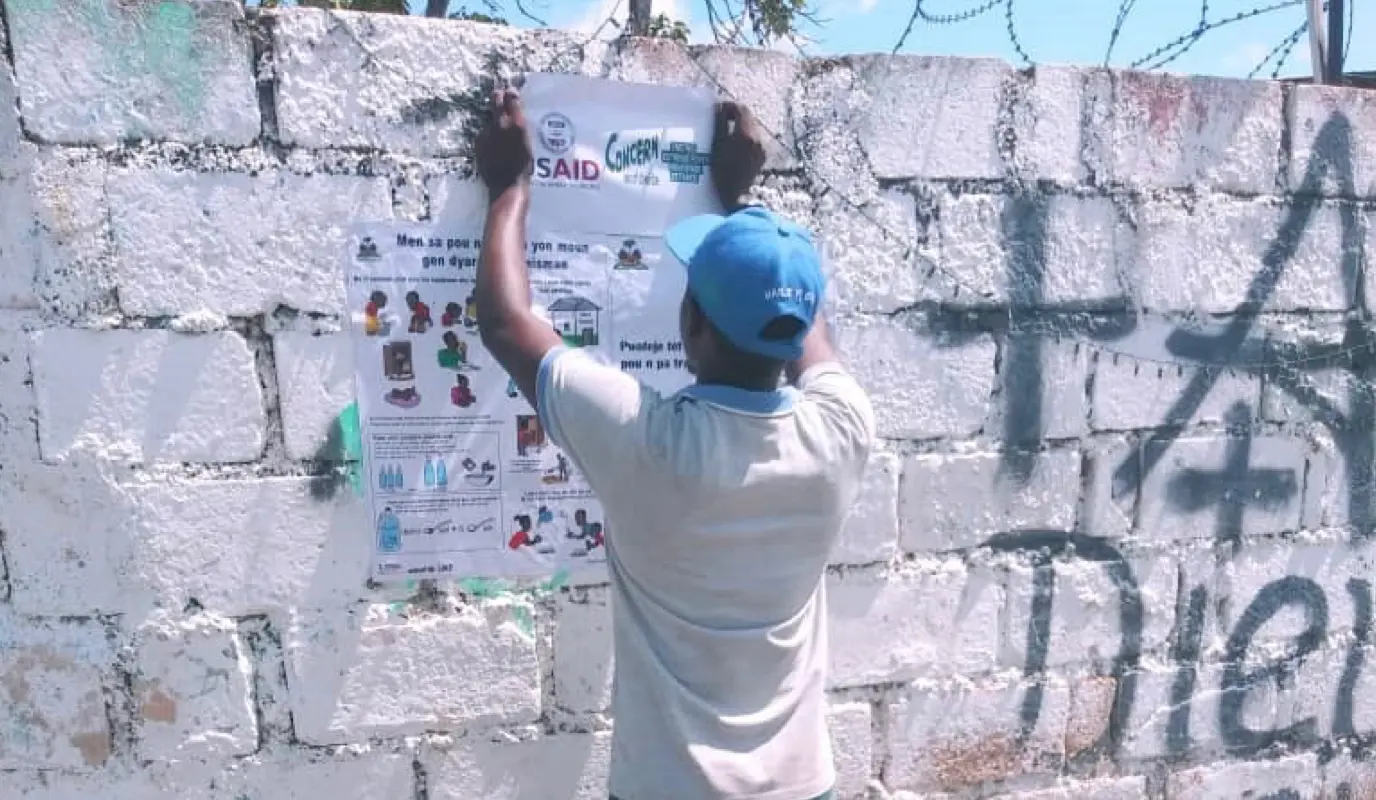 In Cité Soleil, Agents de Sante hang information posters as part of a response to the recent Cholera Outbreak